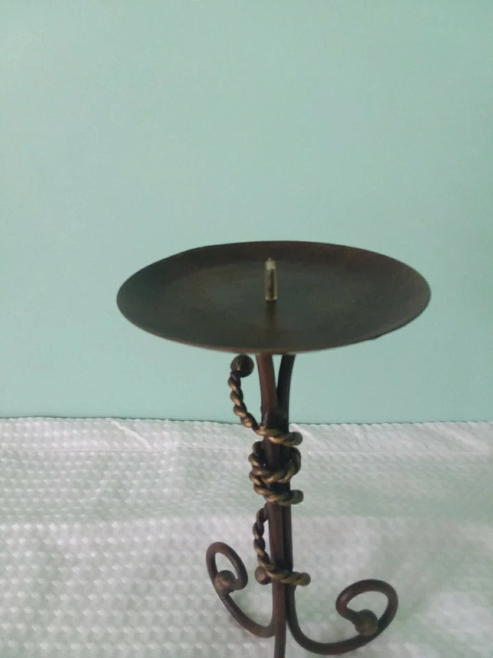 Decorative metal candle holder on a textured surface with a light blue background