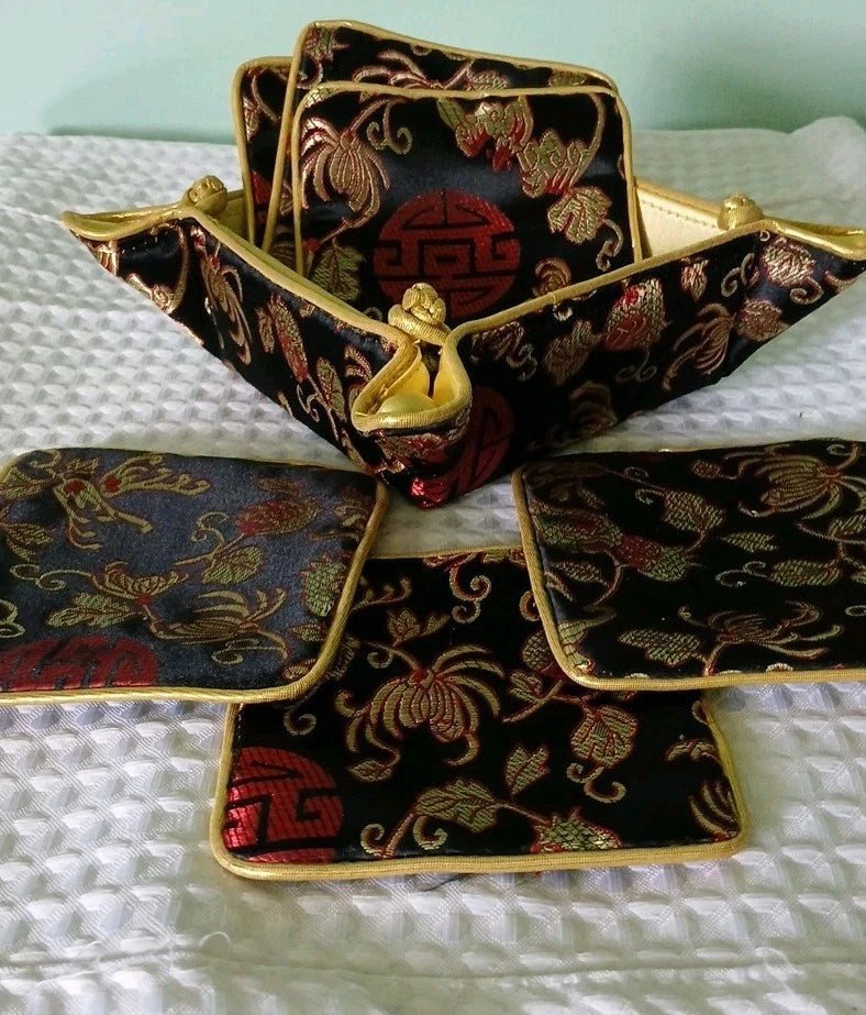Decorative black and gold fabric with intricate patterns on a white textured surface