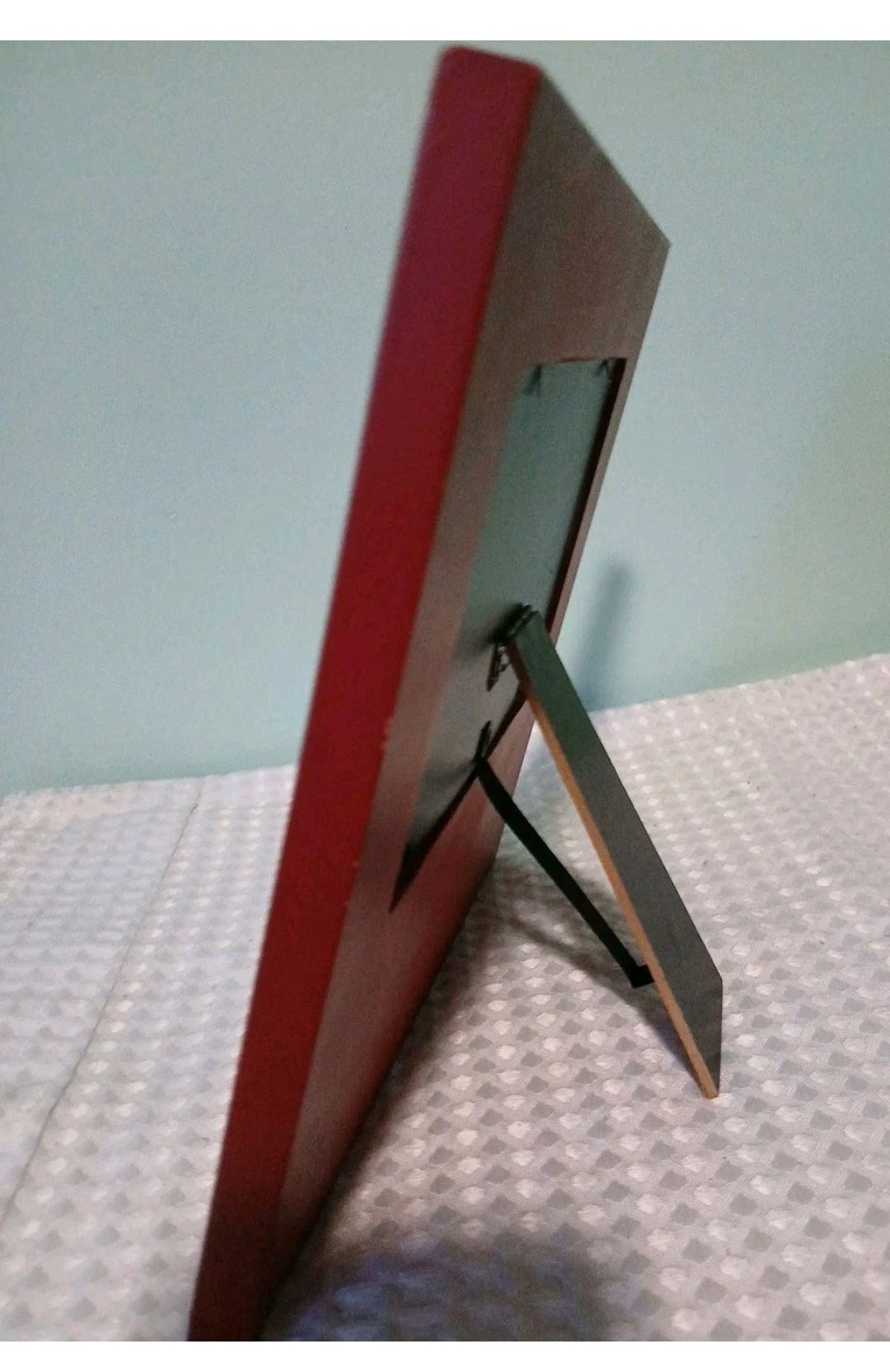 Red picture frame on a textured surface with a light blue background