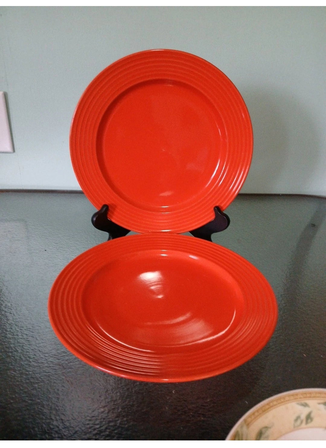 Two orange ceramic plates stacked on a dark surface with a light gray background