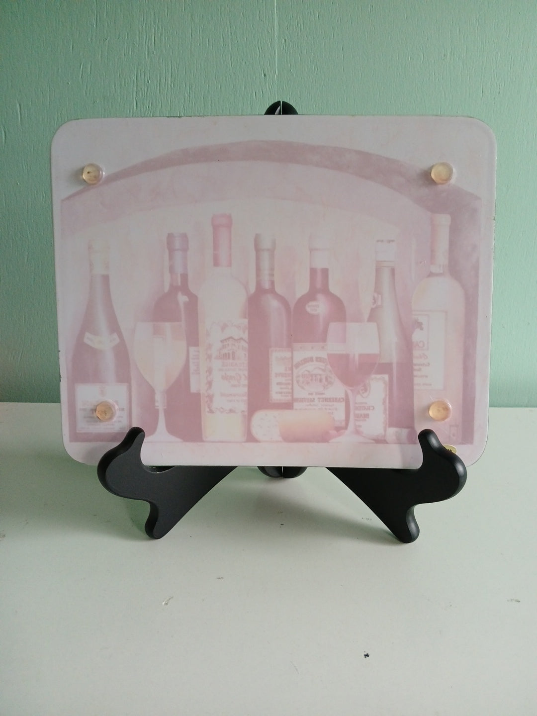back side of the trivet featuring bottles on a green and white background