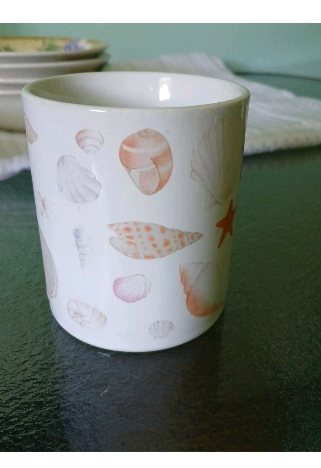 White ceramic cup with shell pattern on a dark surface