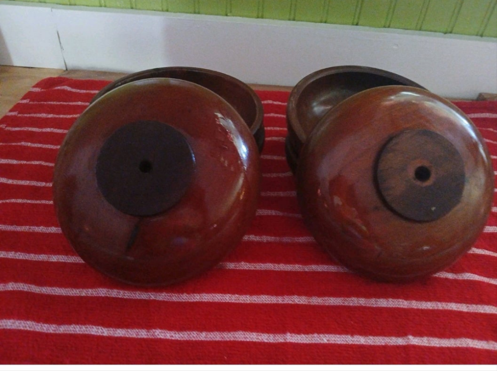 Two wooden bowls with dark brown interiors on a red and white striped fabric background.