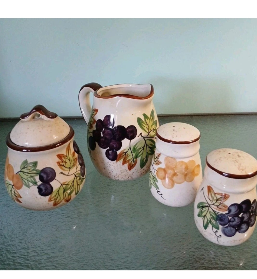 Set of ceramic containers with grape design on a glass surface