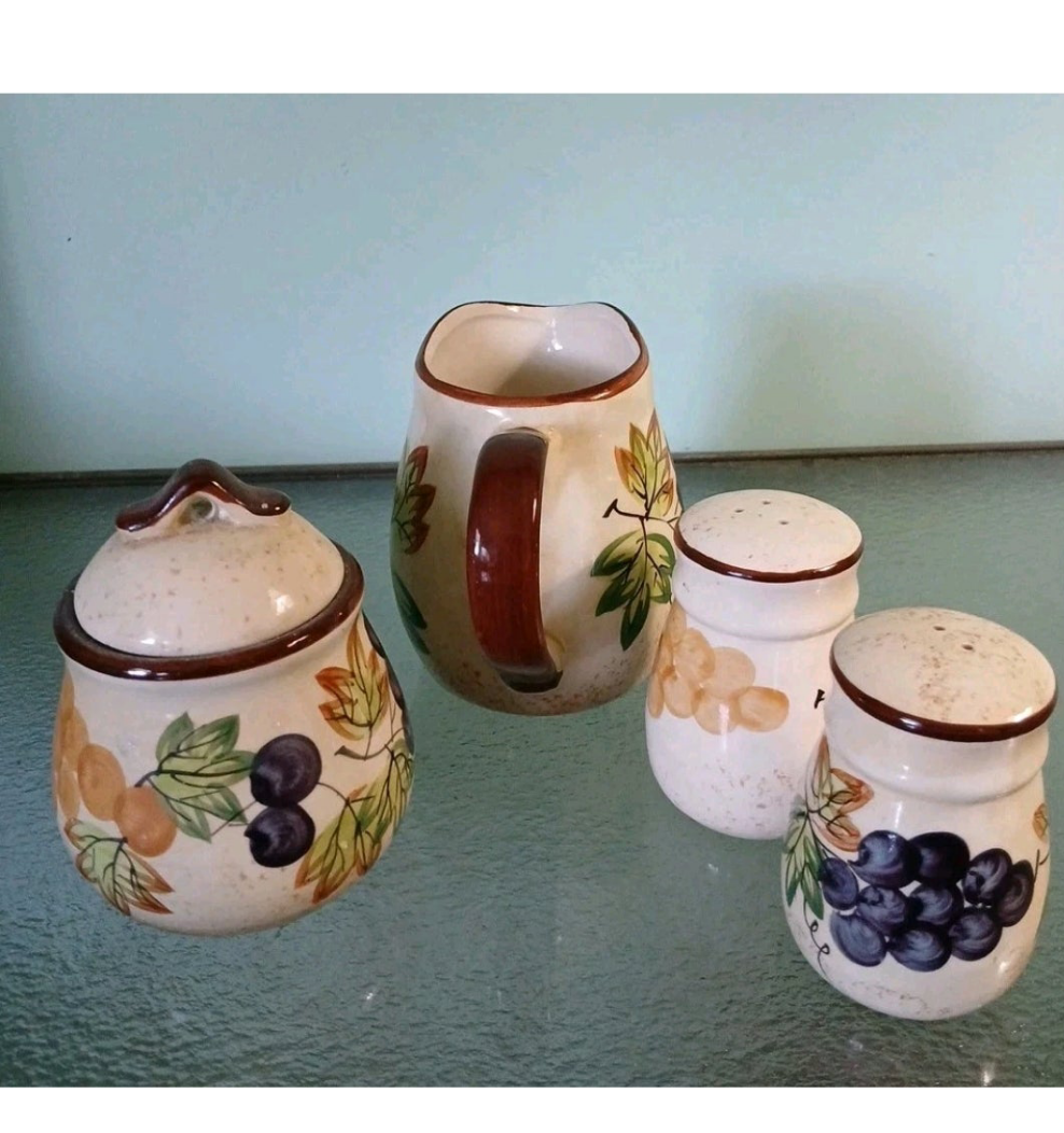 Set of ceramic jars with fruit designs on a reflective surface