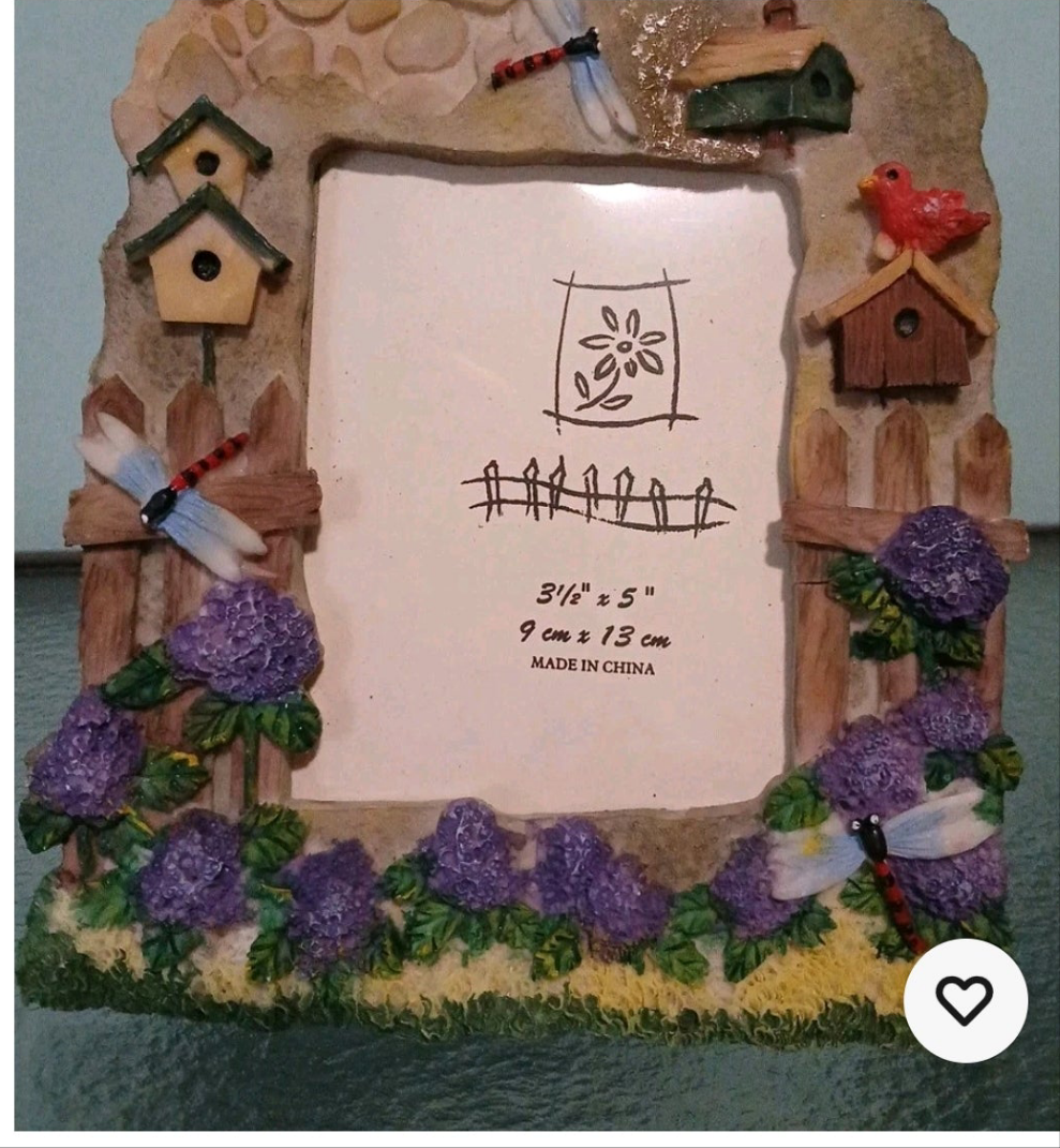 Decorative picture frame with birdhouses, flowers, and a windmill on a plain background