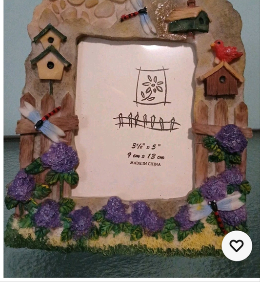 Decorative picture frame with birdhouses, flowers, and a windmill on a plain background