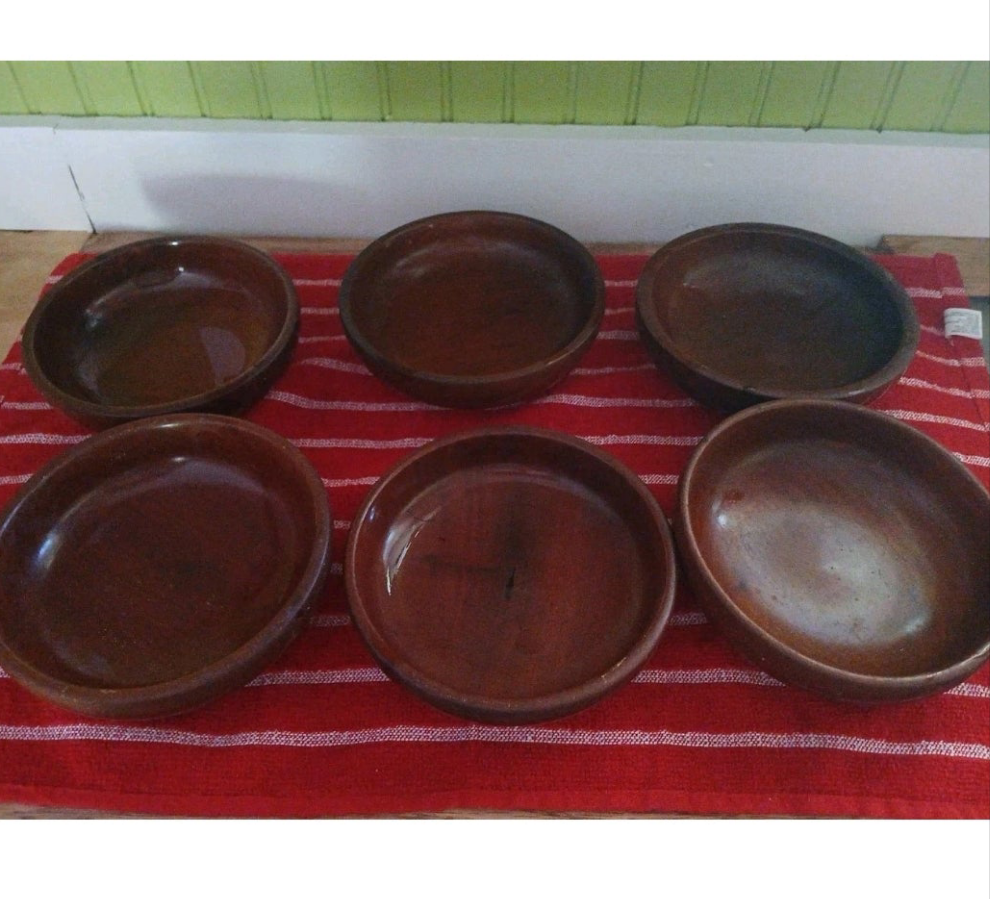 Set of six brown wood bowls on a red and white striped cloth with a green and white background