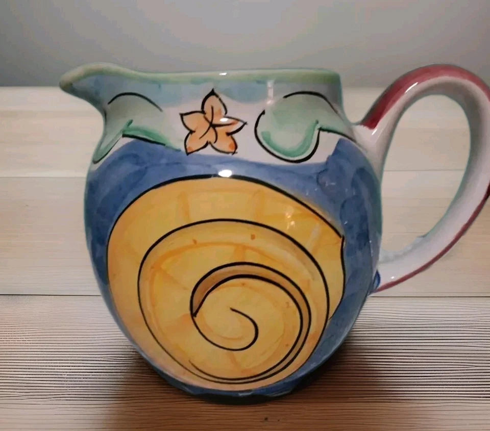 Ceramic pitcher with floral design on a wooden surface