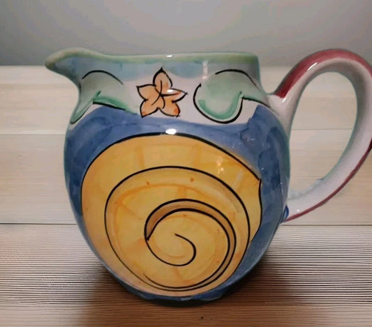 Ceramic pitcher with floral design on a wooden surface