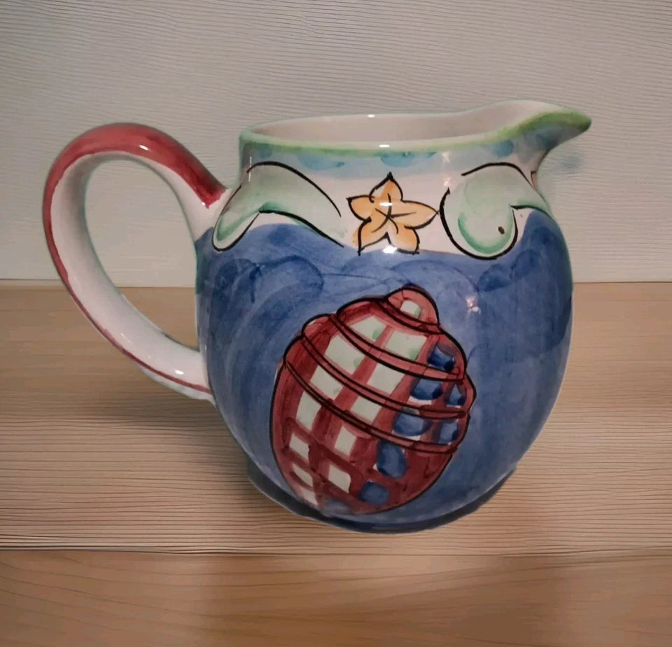 Ceramic pitcher with decorative design on a wooden surface