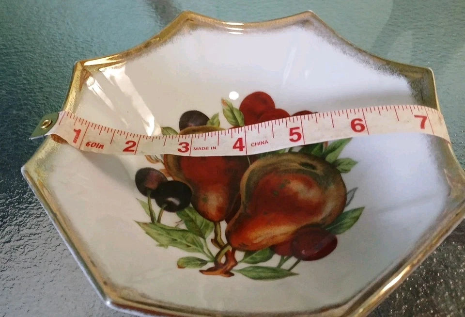 Decorative plate with fruit design and a measuring tape indicating its size.