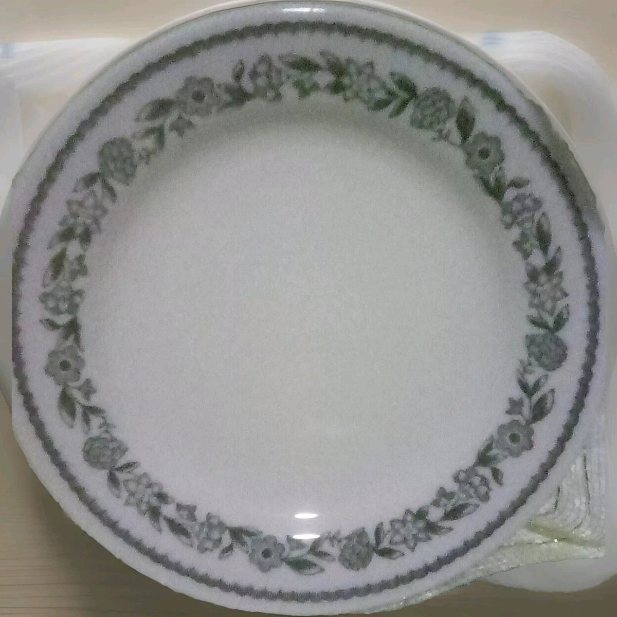 White plate with green floral pattern on a beige surface