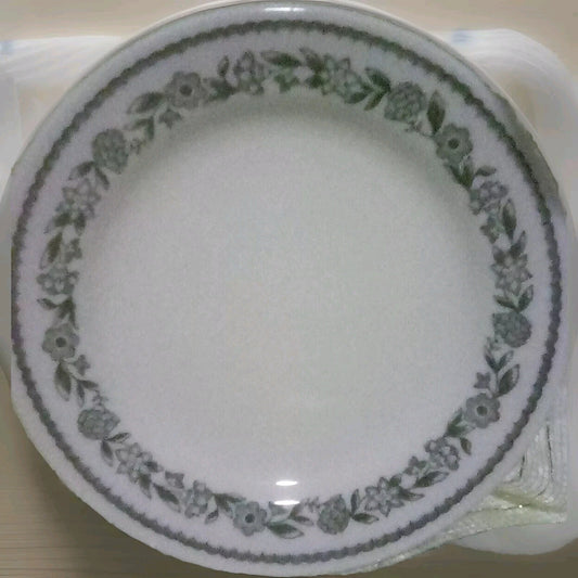 White plate with green floral pattern on a beige surface