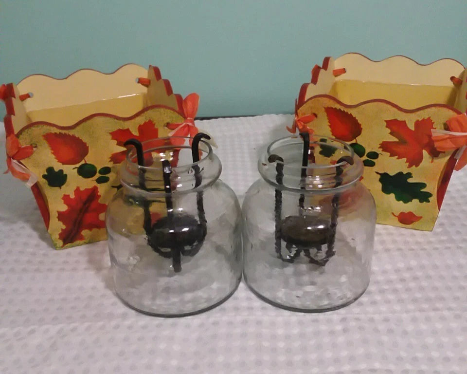 Two glass jars with spider decorations on a white surface with a light blue background.
