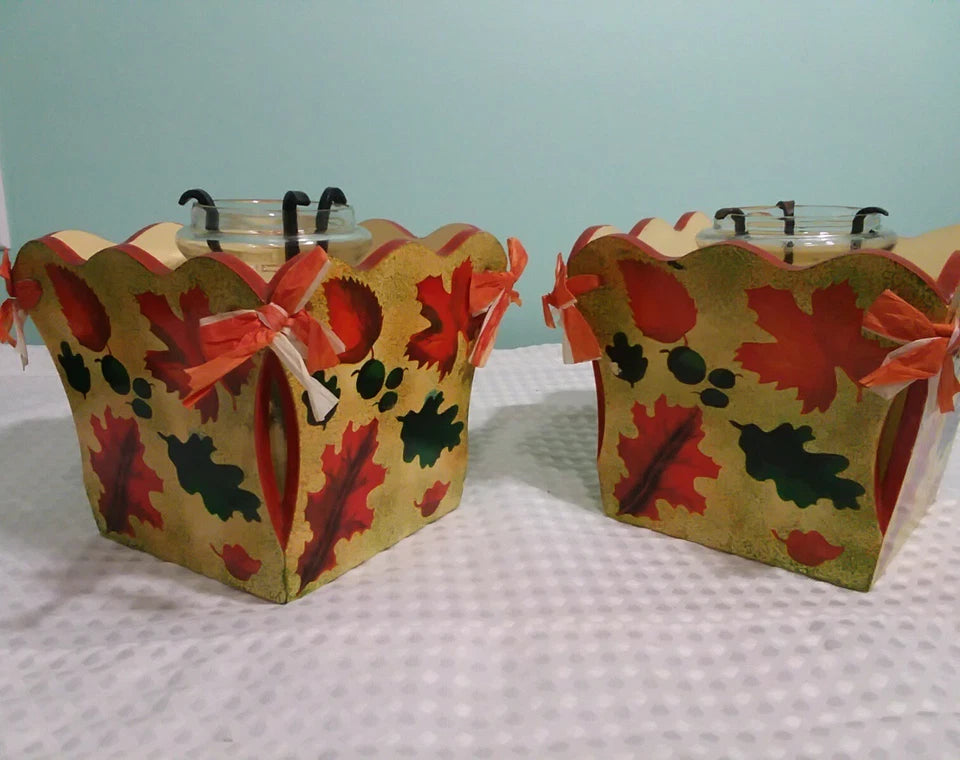 Two decorative boxes with autumn leaf patterns on a checkered tablecloth.