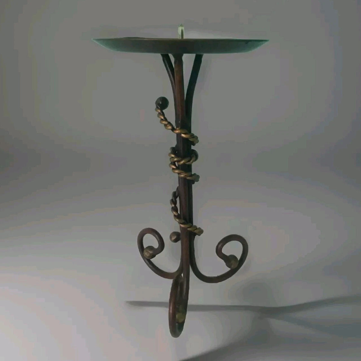 Decorative metal stand with a twisted design on a light gray background