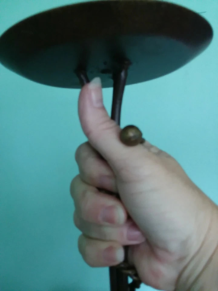 Hand holding a dark metal object against a teal background