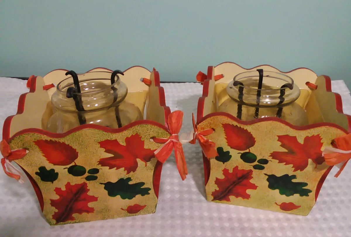 Two decorative candle holders with autumn leaf design on a light blue background
