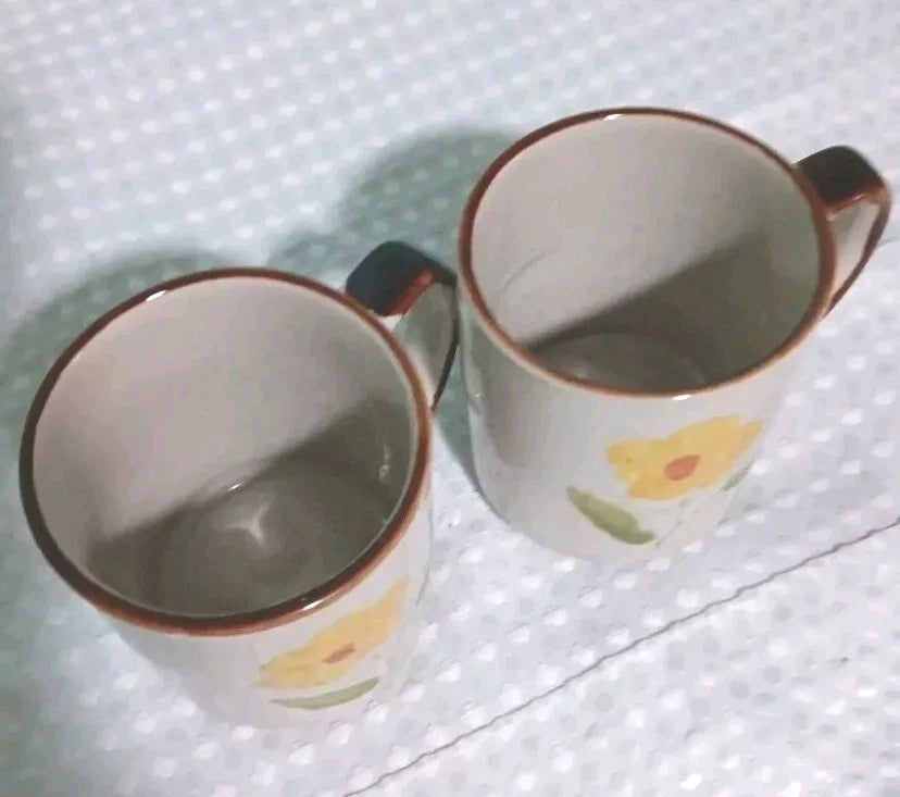 Two ceramic mugs with floral designs on a textured white surface