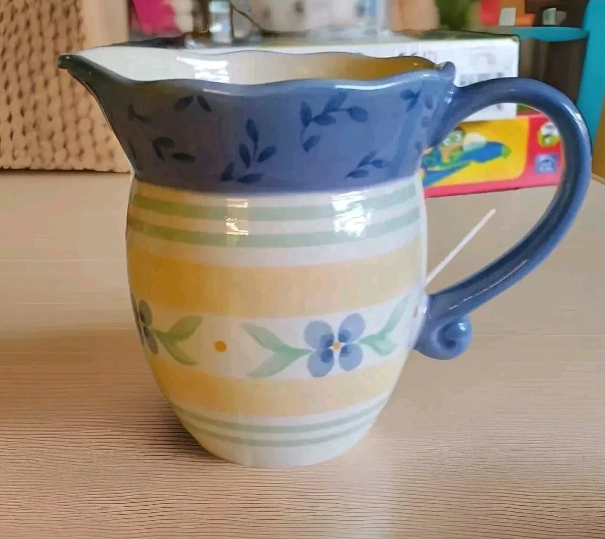 Ceramic pitcher with floral patterns on a wooden surface