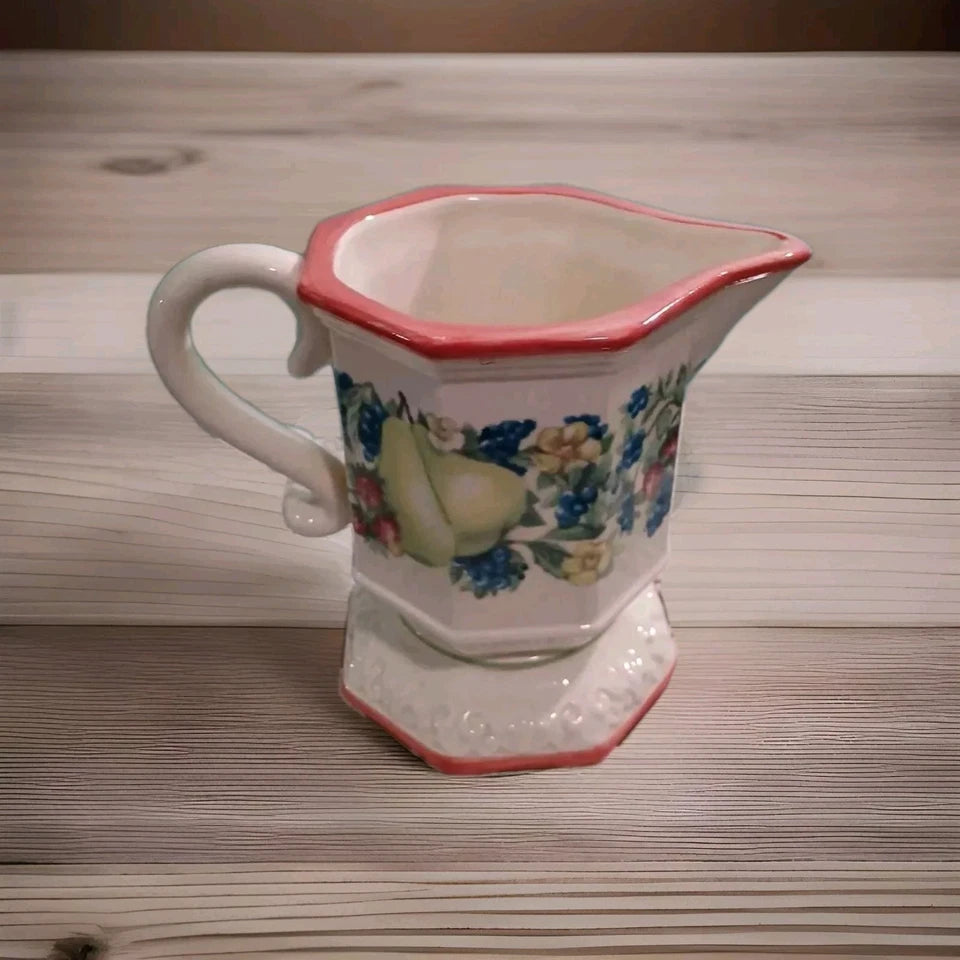 Decorative ceramic pitcher with floral patterns on a wooden surface