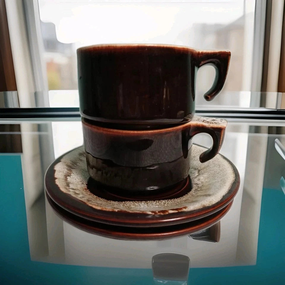 Stack of brown ceramic cups on a saucer with a blurred window background