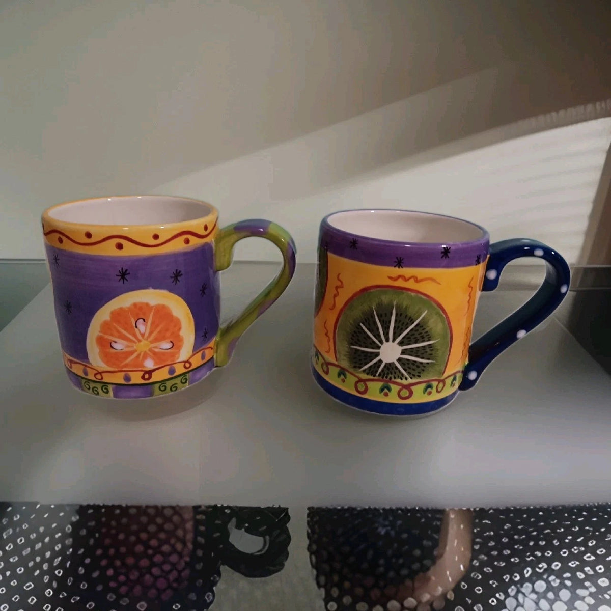 Two colorful mugs with decorative designs on a white surface.
