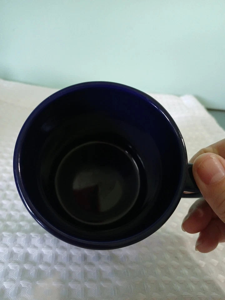 Person holding a blue mug against a light background