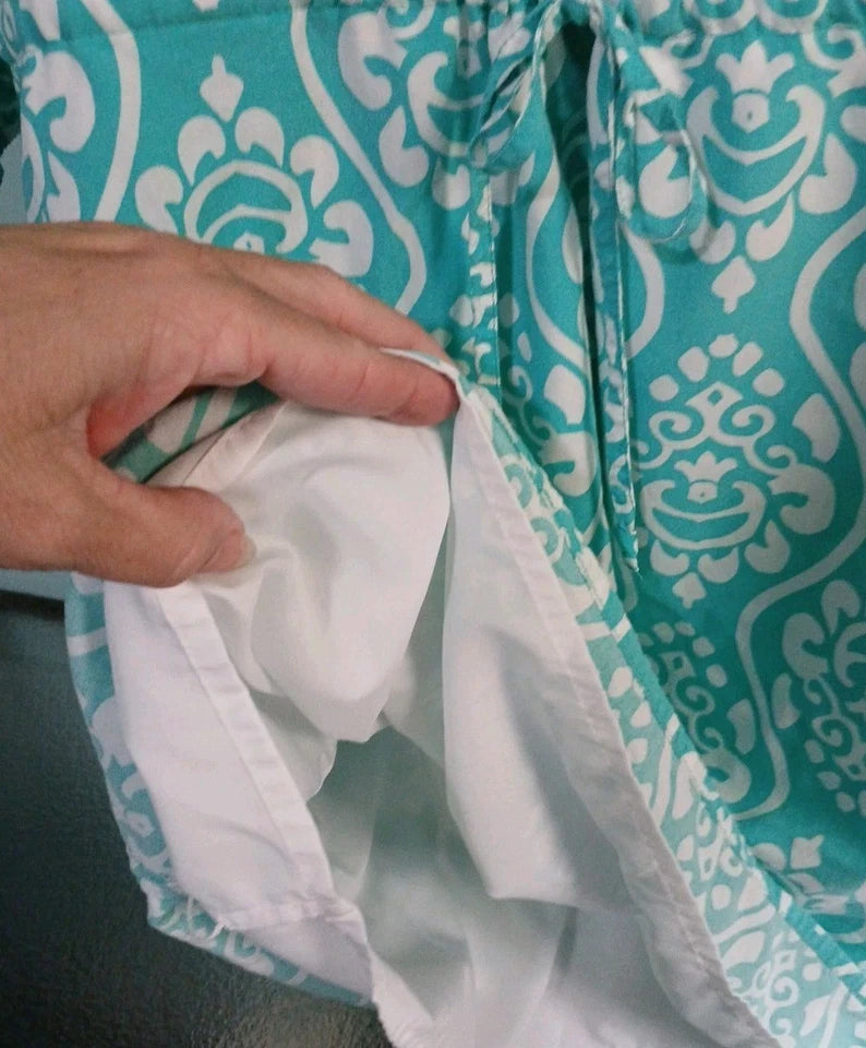 Teal fabric with white pattern held by a hand