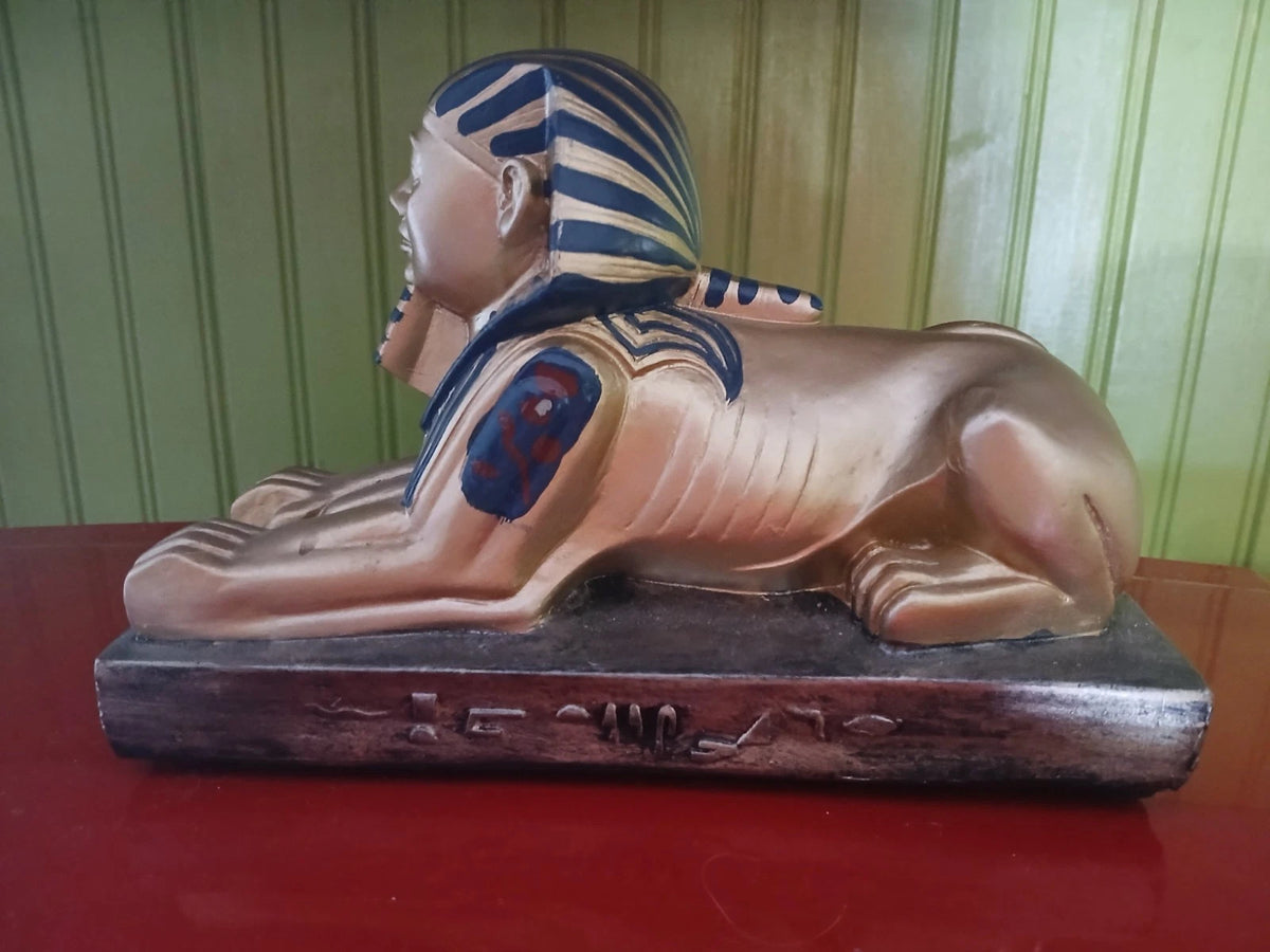 Statue of a sphinx with an Egyptian design on a red surface.