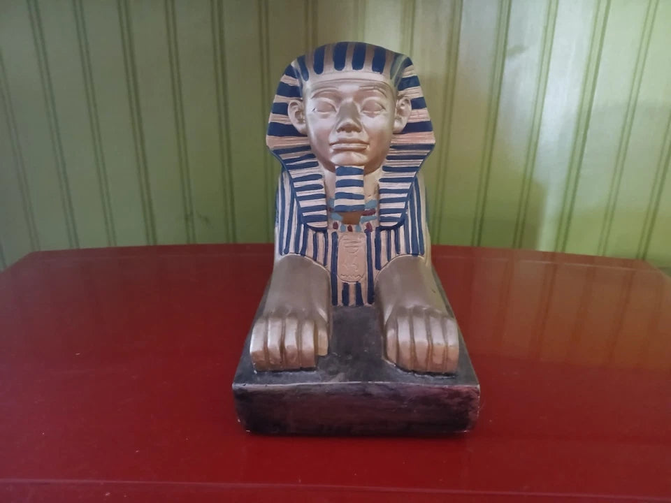 Statue of a pharaoh on a red surface with a green striped background