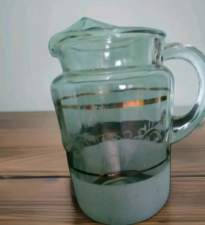 Clear glass pitcher with handle on a wooden surface