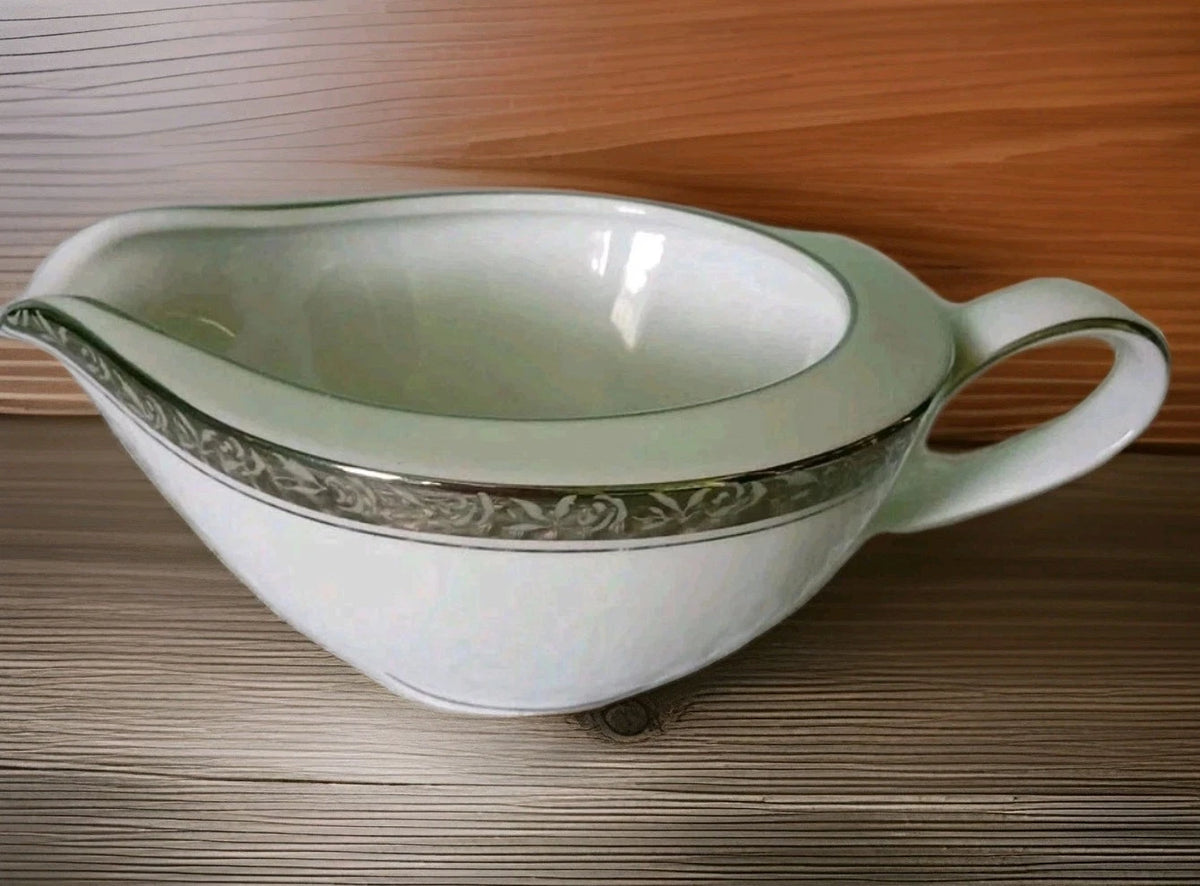 Decorative ceramic gravy boat with floral patterns on a wooden surface