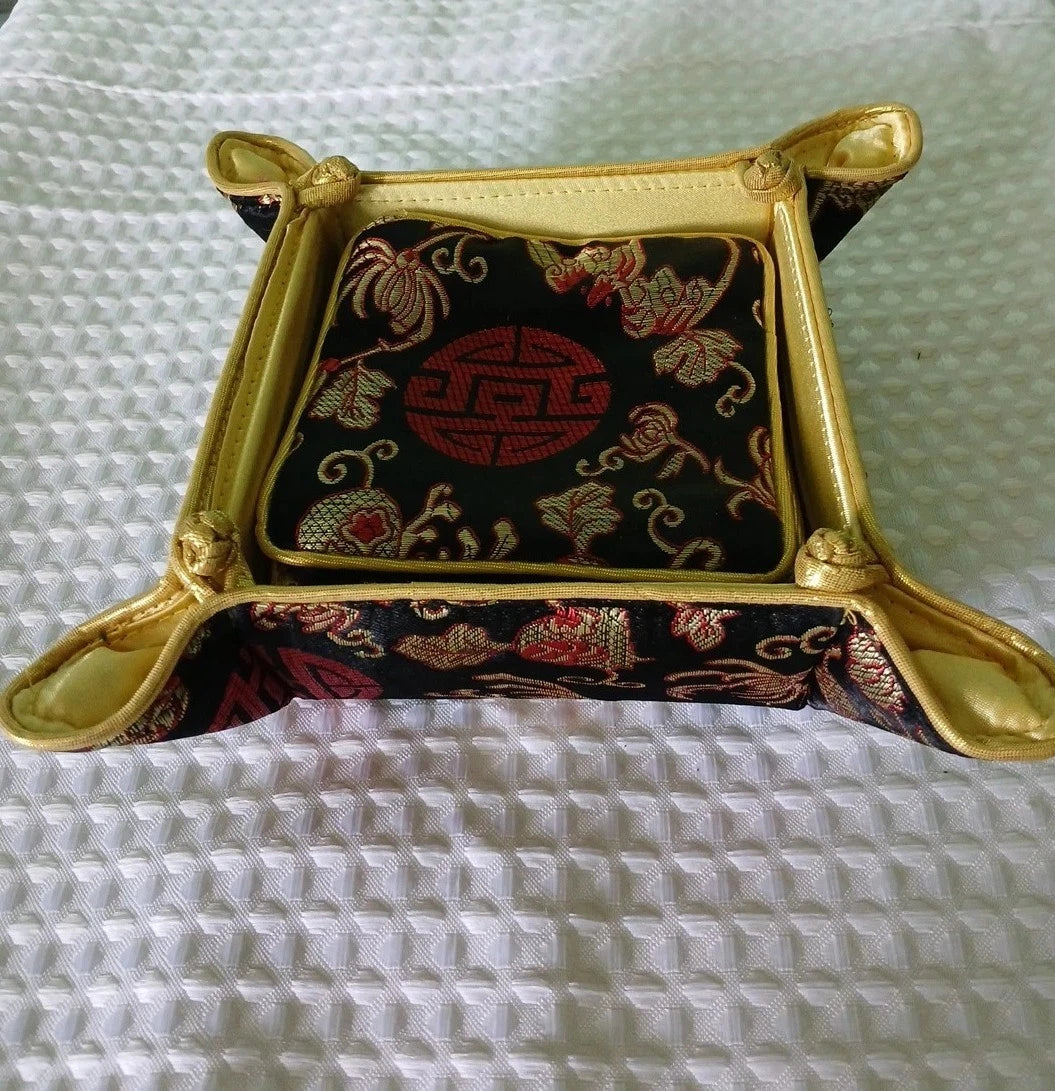 Decorative square box with gold frame and embroidered design on a textured white surface