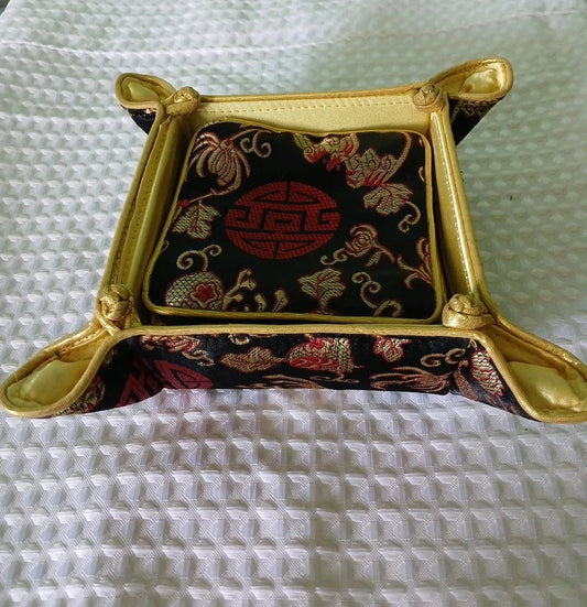 Decorative square box with gold frame and embroidered design on a textured white surface