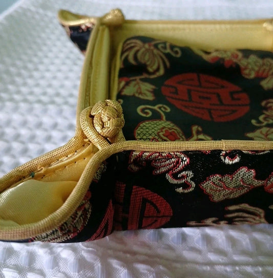 Decorative pouch with gold zipper and intricate patterns on a white textured surface