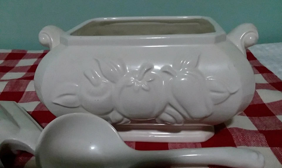 White ceramic planter with decorative design on a red and white checkered tablecloth.