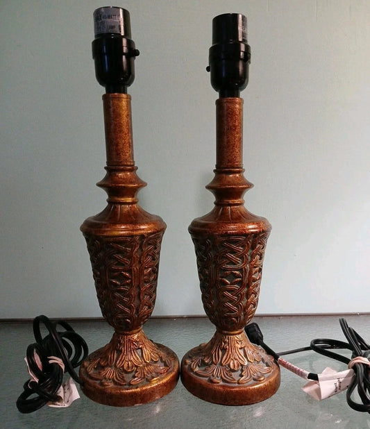 Pair of ornate wooden table lamps with intricate carvings on a plain background