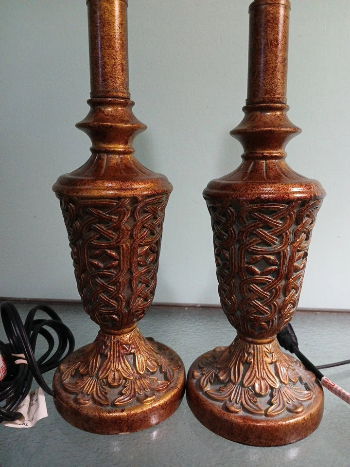 Pair of ornate wooden lamps with intricate carvings on a neutral background