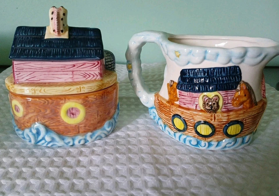 Two ceramic items shaped like Noah's Ark on a textured surface.