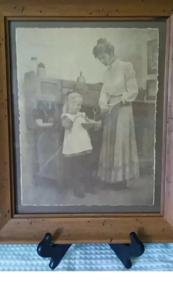 Vintage photograph of a woman and child in a wooden frame on a blue textured surface.