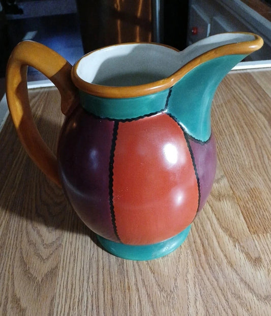 Colorful ceramic pitcher on a wooden surface
