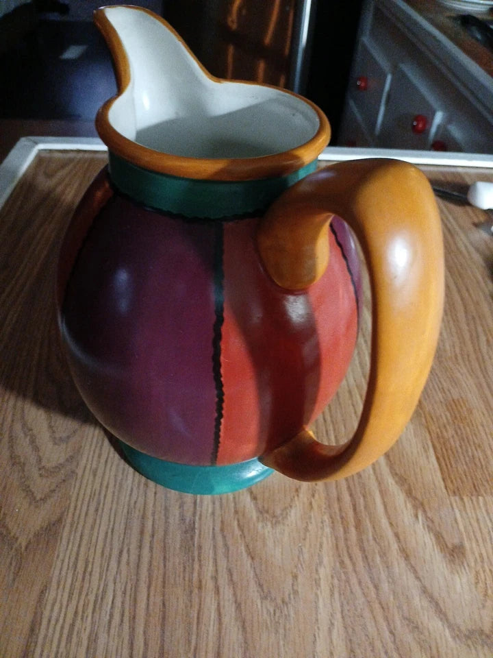 Colorful ceramic pitcher on a wooden surface