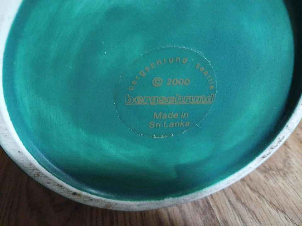 Close-up of a green ceramic plate with branding and text on a wooden surface