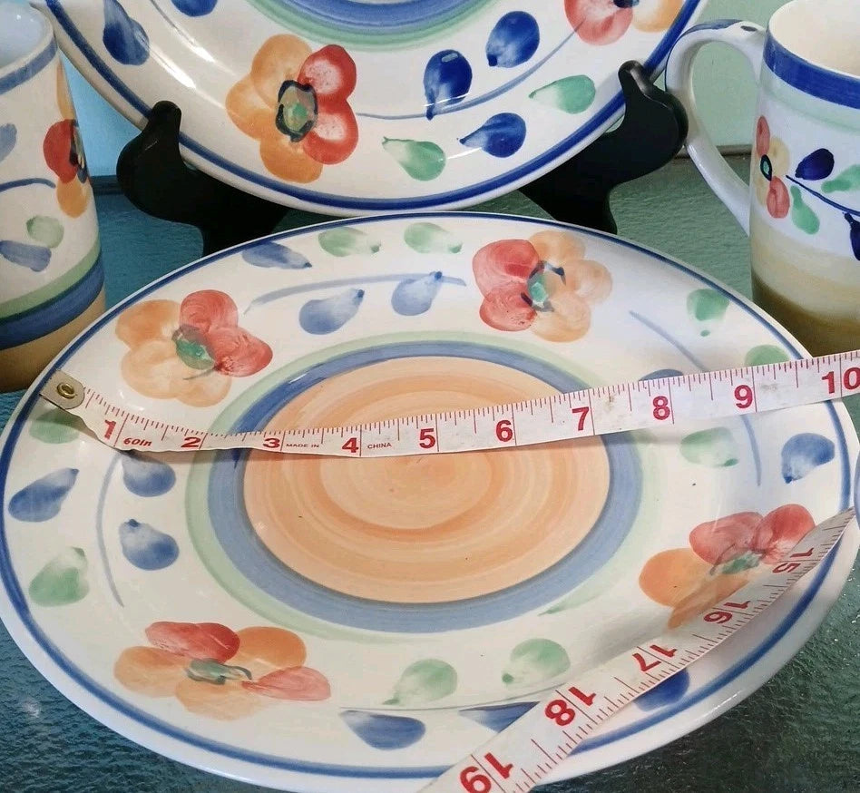 Decorative ceramic plate with floral designs and a measuring tape on top, placed on a green surface.