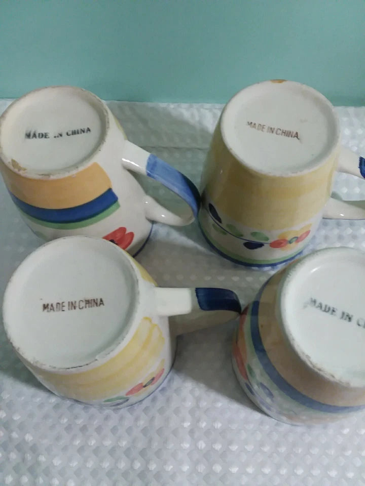 Four ceramic mugs with colorful designs and 'Made in China' text on a polka dot surface.