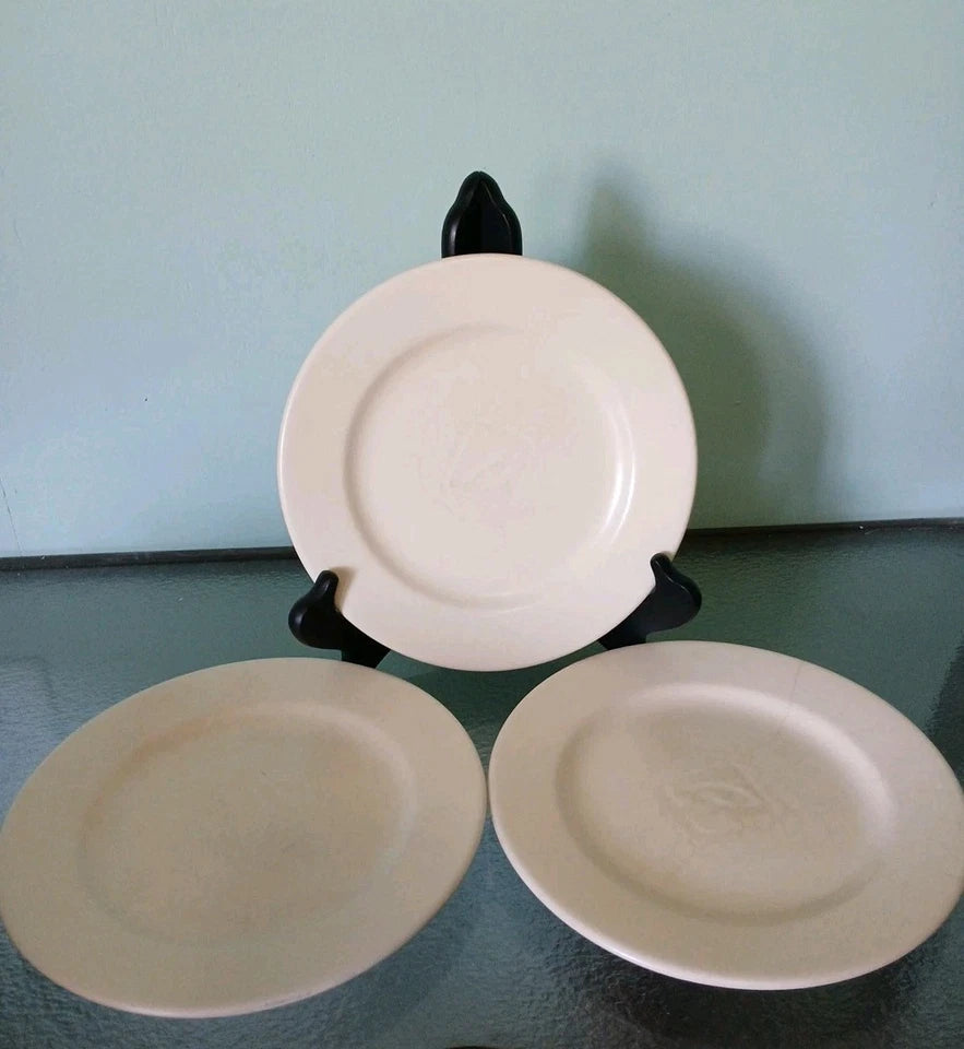Three ceramic plates on a stand against a light blue wall.