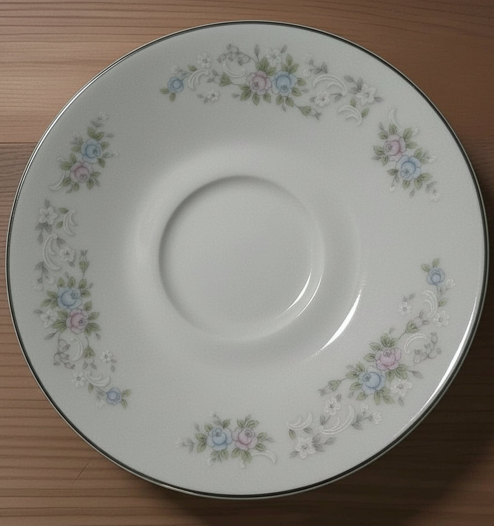 White ceramic saucer with floral patterns on a wooden surface
