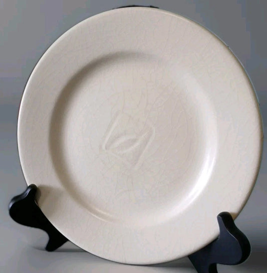 White ceramic plate on a black stand against a gray background